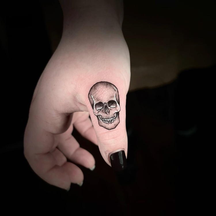 Tatuagem pequena e sombreada de caveira no dedo 