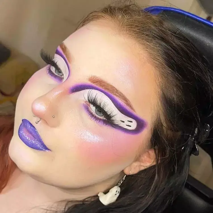 mulher com maquiagem em tons de roxo, olhos com desenho de fantasma