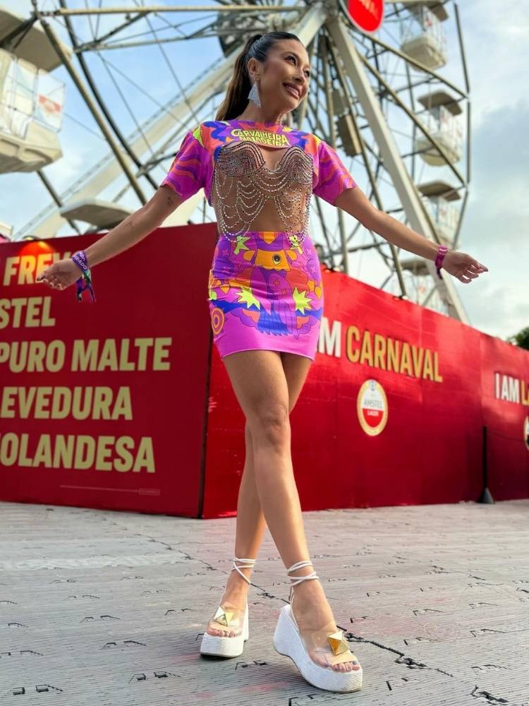 Mulher de pele clara usando abadá roxo em cropped e saia, com top de miçangas