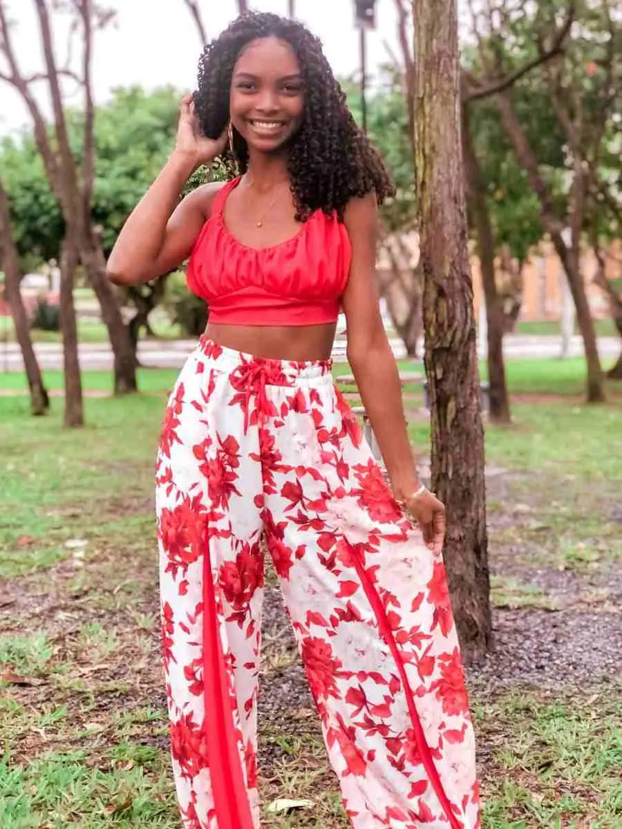 Mulher de pele negrs usando look cropped + calça vermelho floral para o Natal.