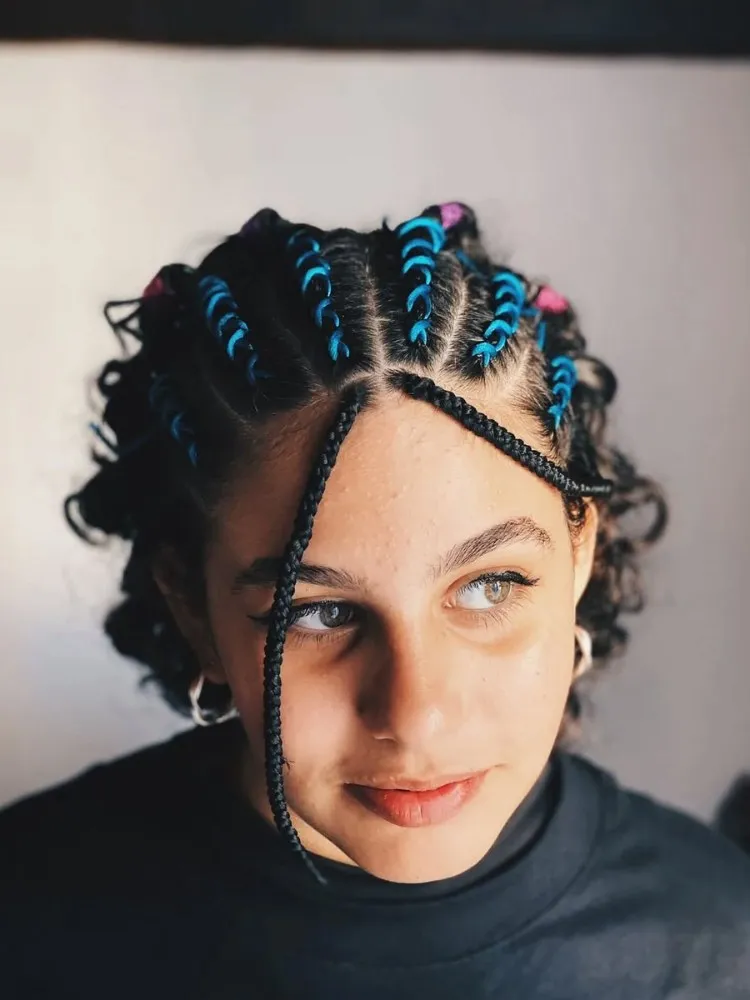 Mulher de pele clara com cabelo curto em tranças nagô com elásticos coloridos 