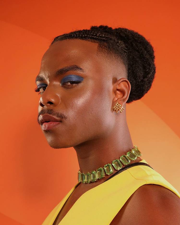 Homem com penteado afro trançado + make azul nos olhos e batom