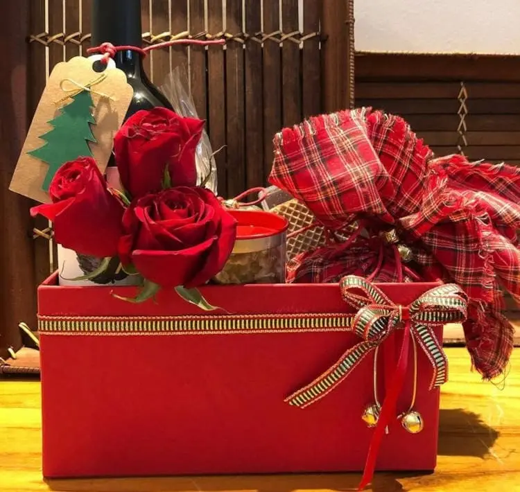 Cesta vermelha de Natal com flores, panetone embrulhado em tecido vermelho, cartão de natal e mais 