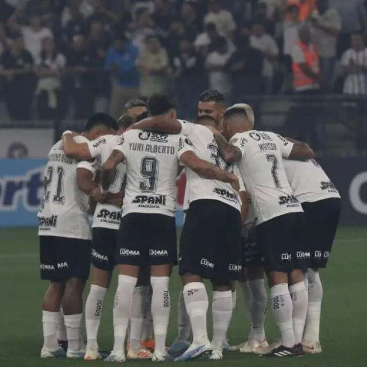 Elenco do Corinthians se abraçando no gramado e utilizando o primeiro uniforme.