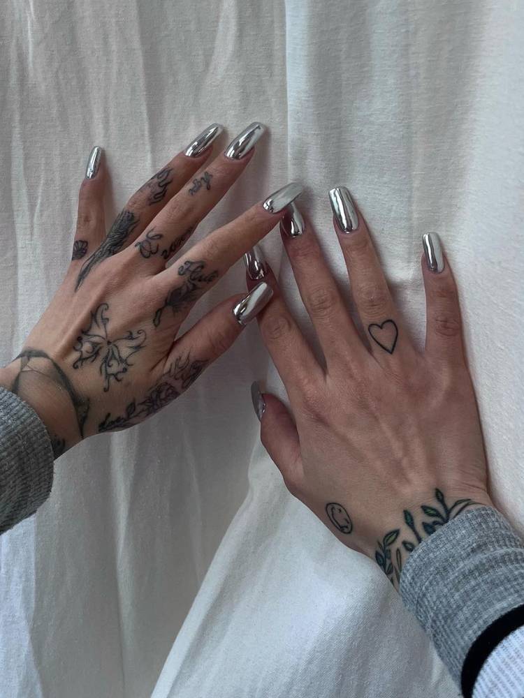 Pessoa tatuada de pele clara com uunha cromada prateada em formato quadrado