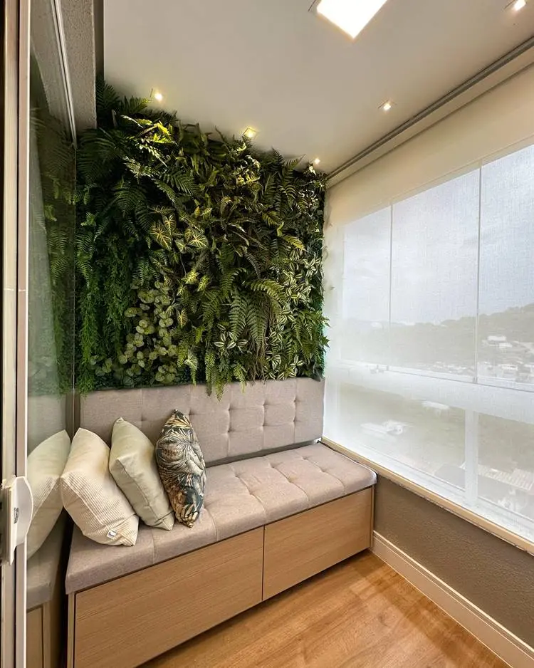 Parede com plantas e um estofado embaixo com almofadas