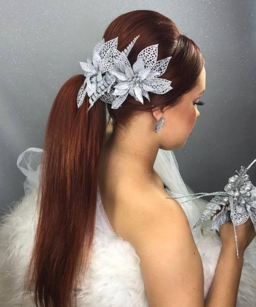 Mulher de pele clara com cabelo volumos, rabo de cavalo e flores prateadas