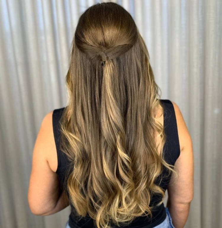 Mulher de pele clara usando penteado enrolado atrás em cabelo loiro escuro