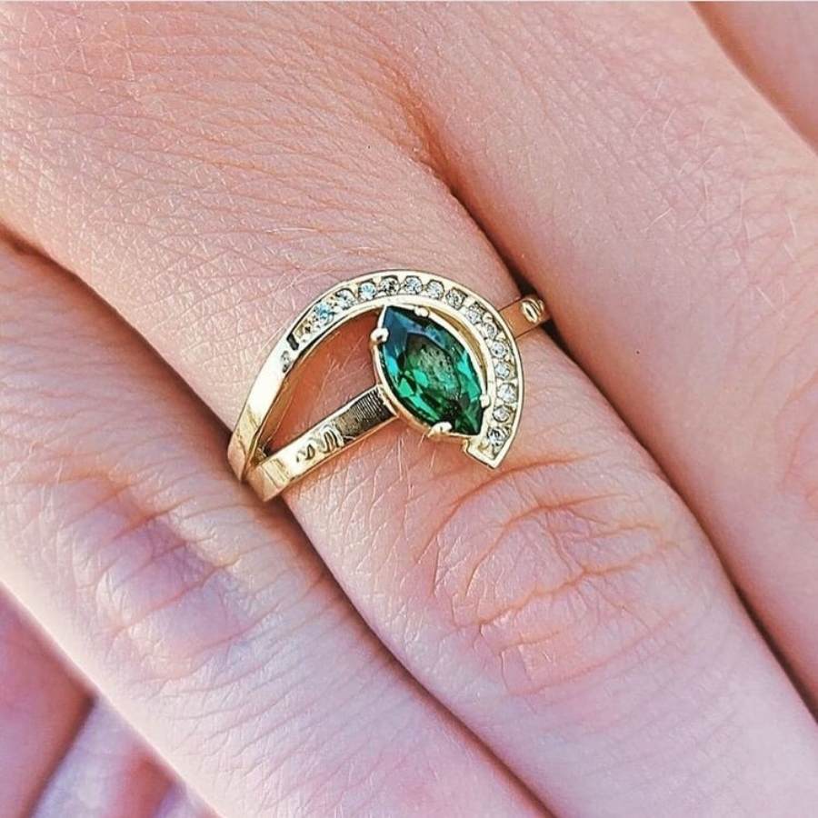 Pessoa de pele com anel fino em ouro, pedra oval verde e detalhe em brilhante