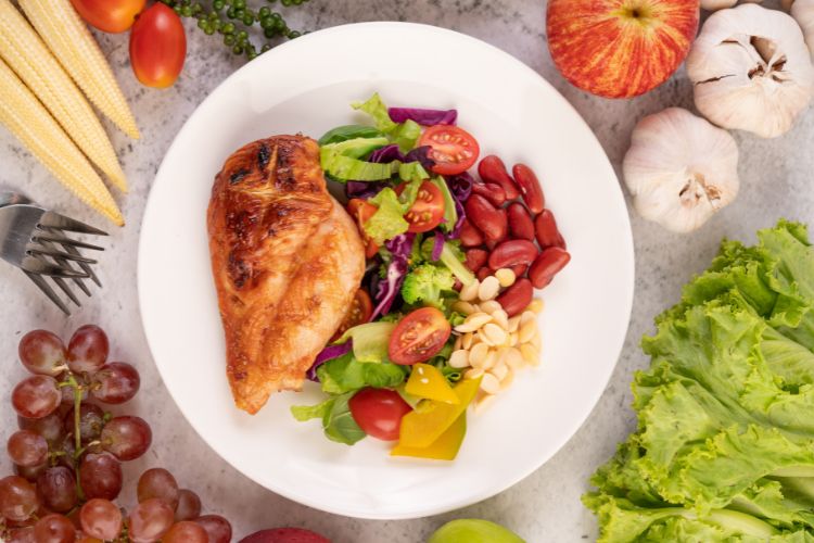Prato com filé de frango, legumes, salada, leguminosas e oleaginosas.