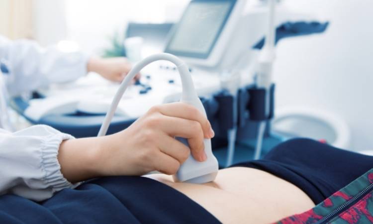 Médico realizando exame de ultrassom na barriga de uma mulher