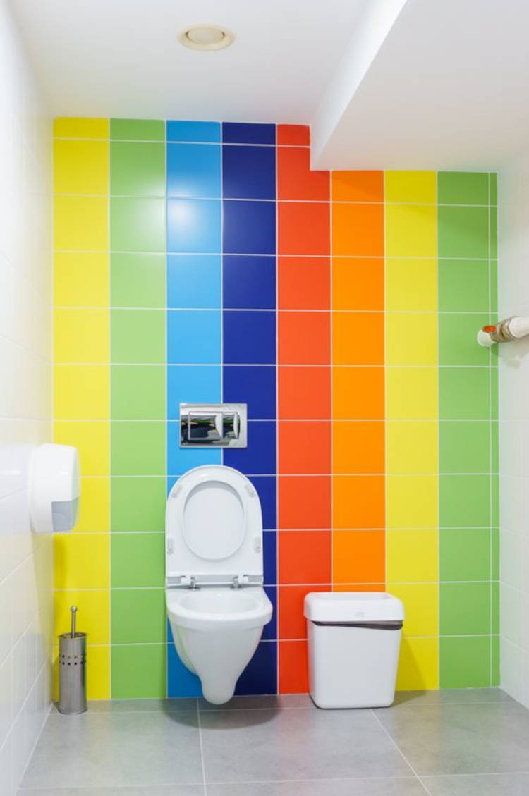 Banheiro branco com azulejos nas cores da bandeira LGBTQIA+