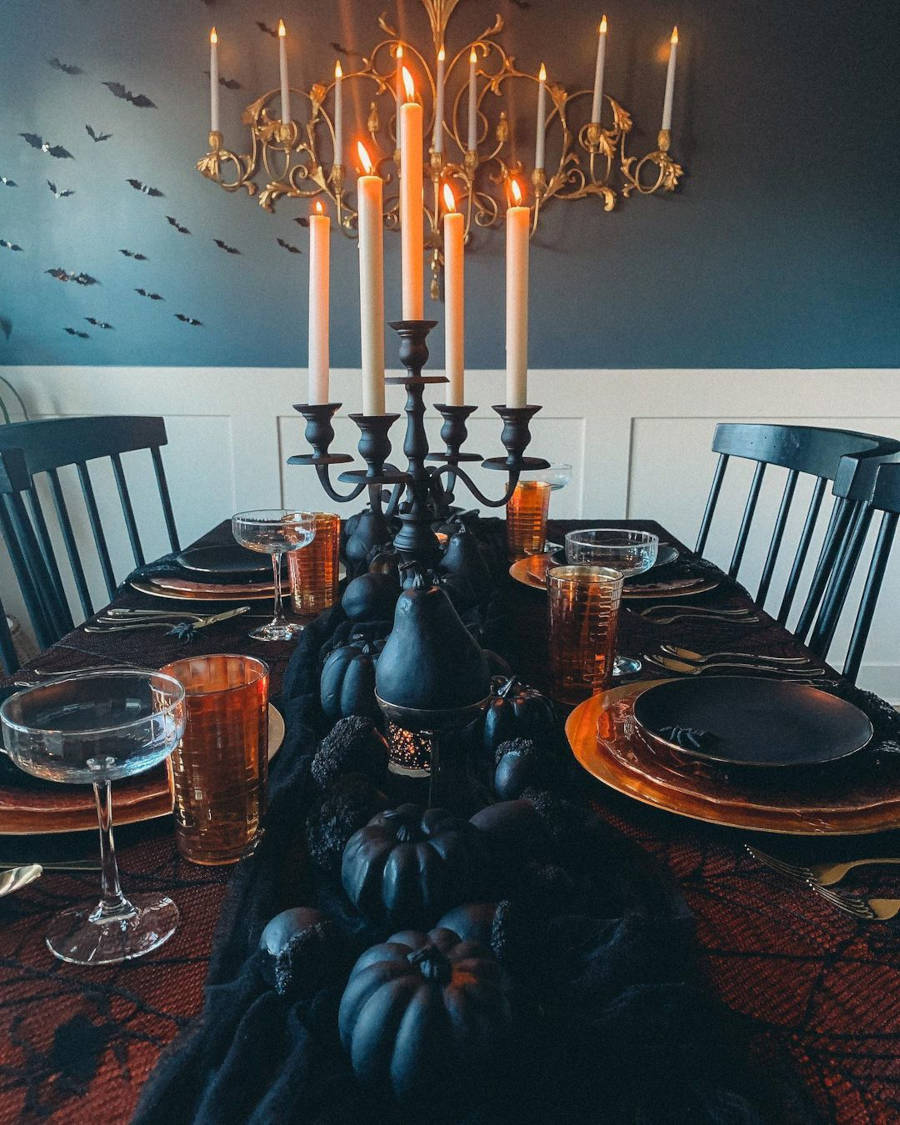 Mesa posta de Halloween com decoração preta: pera, abóbora, castiçal, centro de mesa