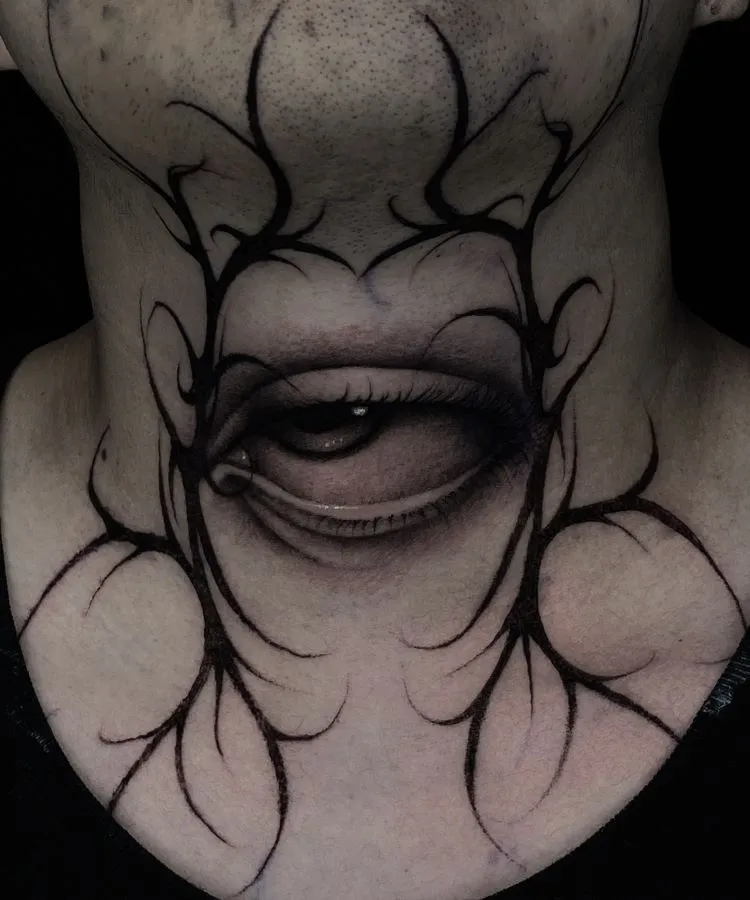 A imagem mostra uma pessoa com uma tatuagem no pescoço de um olho realista, com detalhes sombreados em preto e cinza. Ao redor do olho, há linhas abstratas que se estendem pela pele. A tatuagem ocupa grande parte da frente do pescoço, criando um efeito marcante.


