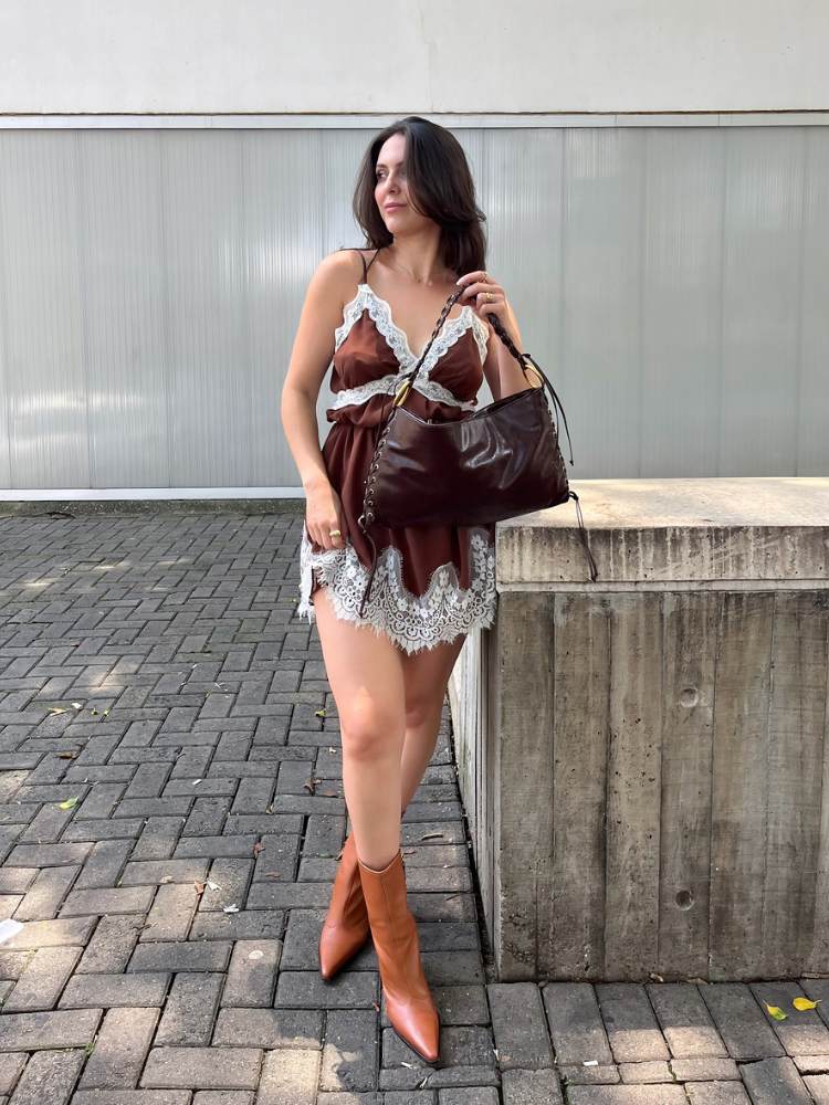 Mulher de pele clara usando slipdress curto marrom com renda e bota cano baixo 