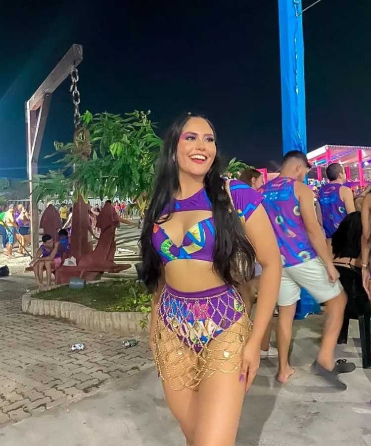 Mulher de pele clara usando abadá roxo customizado de Carnaval de cropped, top e hot pant com saia vazada de correntes.