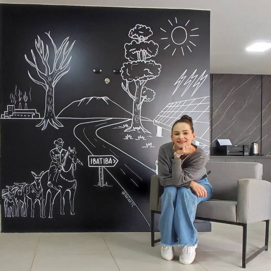 Mulher desenhista de parede de lousa.