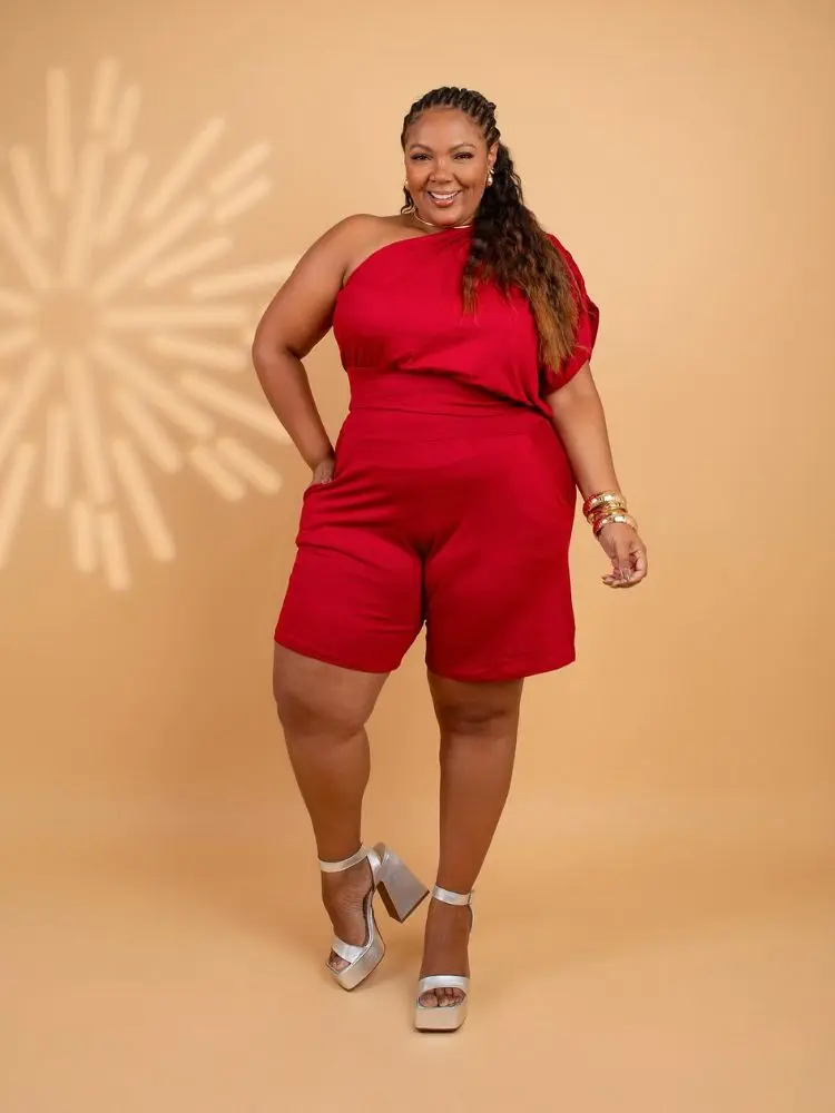 Mulher de pele negra usando conjunto de blusa vermelha ombro só e bermuda vermelha