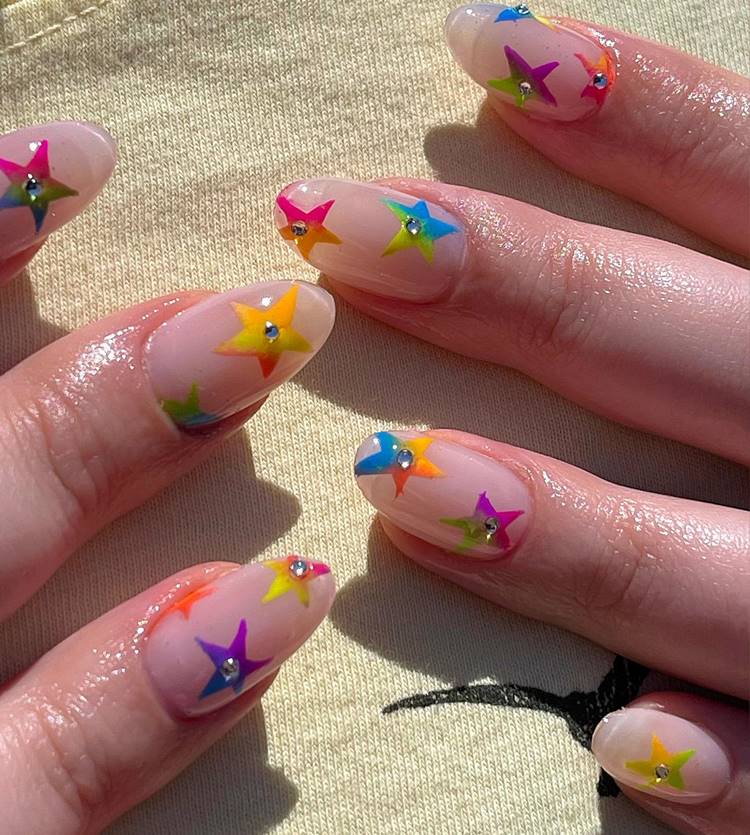Unha para Carnaval com fundo bege + estrelas coloridas com pedraria 