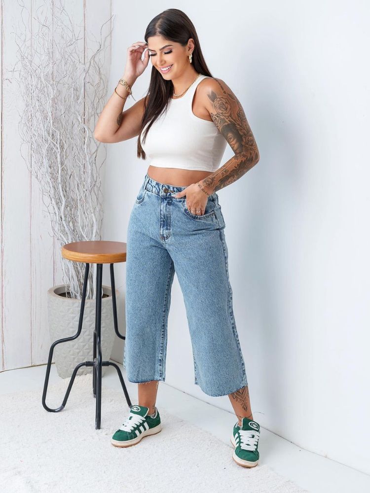 Mulher de pele clara com cropped branco e calça jeans pantacourt