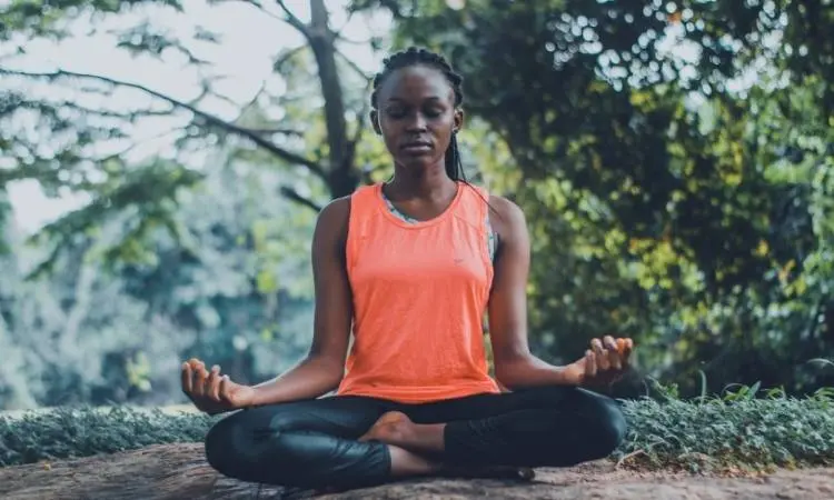 Mulher meditando com roupa de academia.