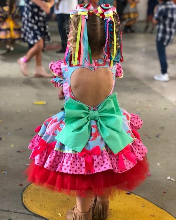 Menina com vestido de quadrilha com laço grande e recorte coração nas costas