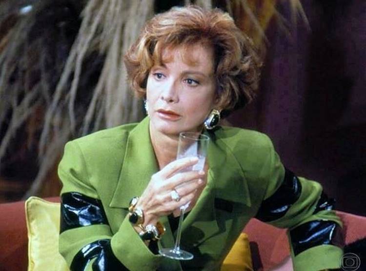 A atriz jovem usando terno verde em cena de alguma novela