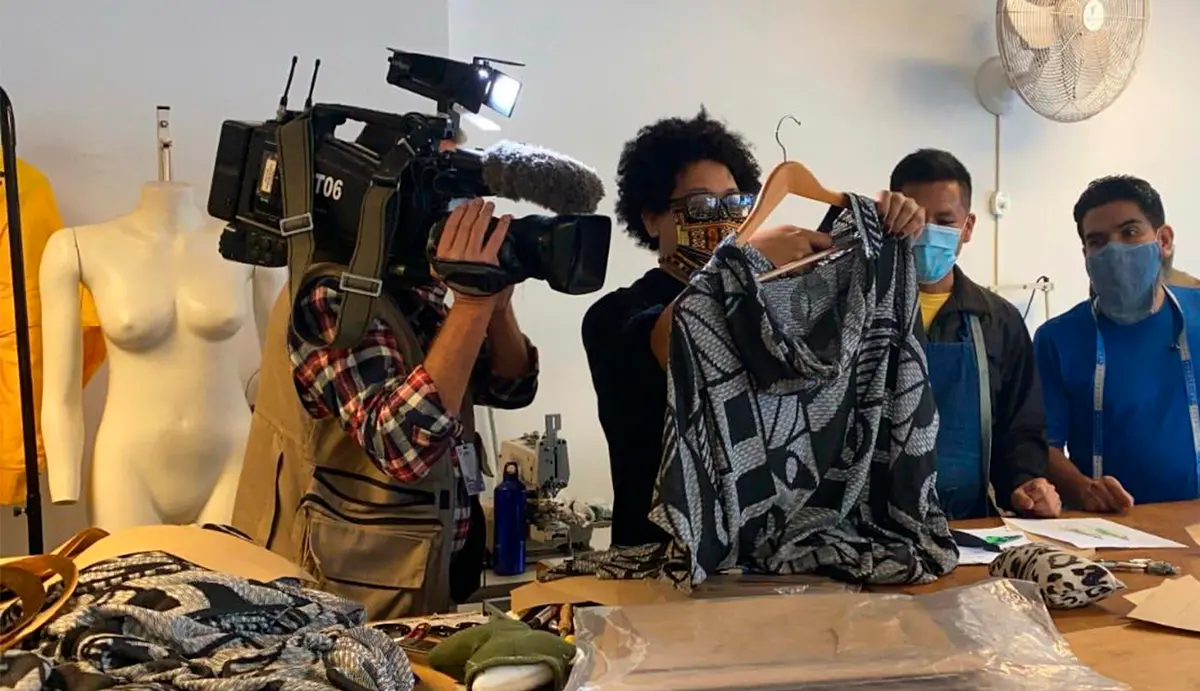 Estilista Isaac Silva é filmado enquanto segura uma de suas criações na mão.