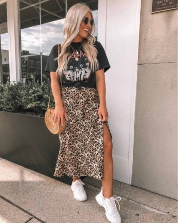 Mulher de pele clara com blusa preta de banda e saia midi de onça