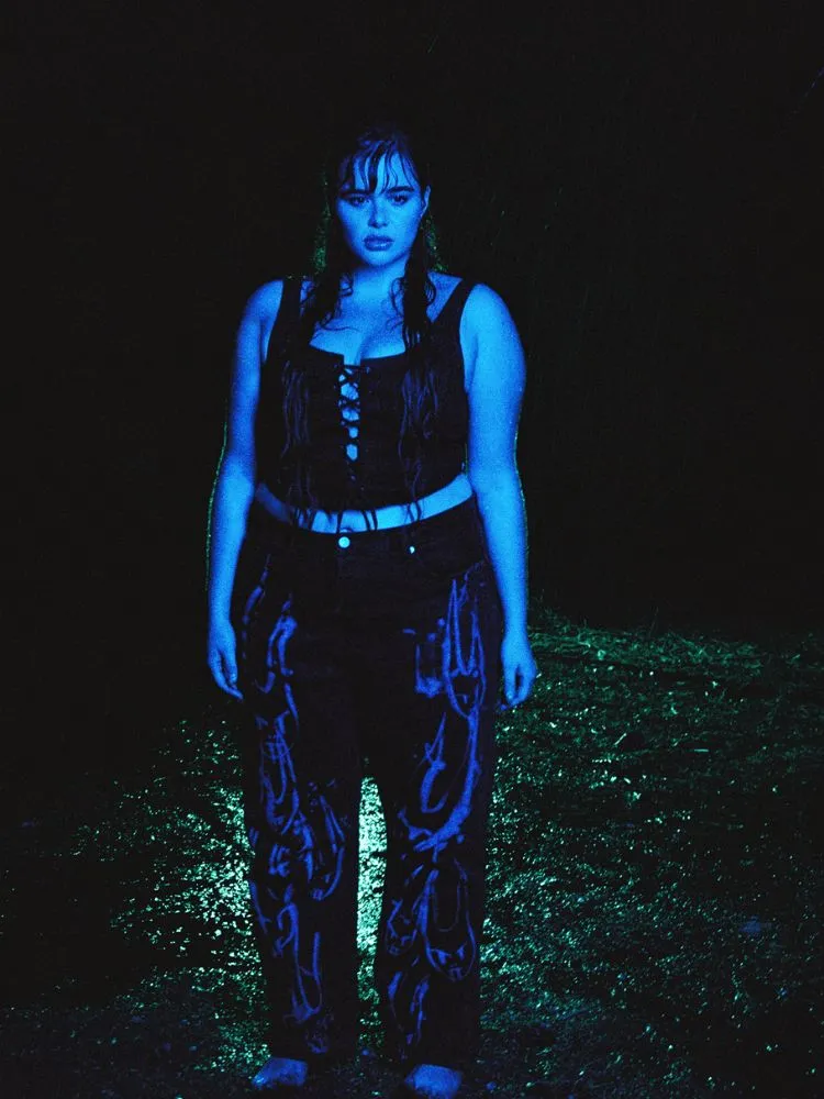 Um look com um corset preto e uma calça jeans preta com estampas em cinza