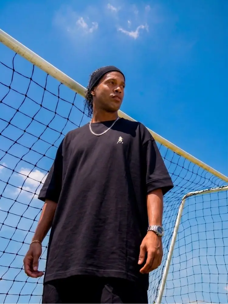 Ronaldinho Gaúcho usando camiseta preta oversized de sua marca de roupas