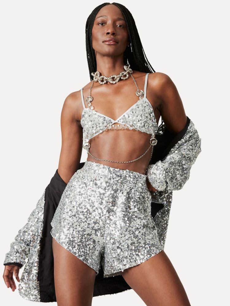 Mulher de pele negra usando top, shorts e kimono de lantejoulas prateadas
