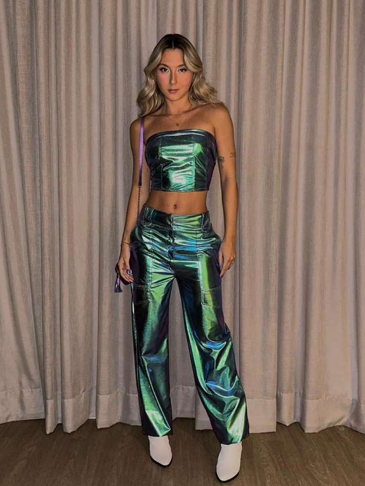 Mulher loira de pele clara usando conjunto de calça e cropped tomara que caia holográficos