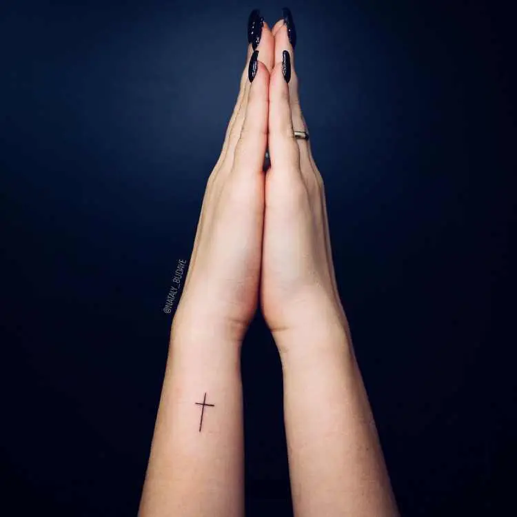 mãos unidas em modo de oração e tatuagem de cruz no pulso, parte lateral