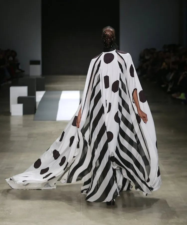 Foto de modelo na passarela usando vestido longo branco com bolinhas e listras pretas
