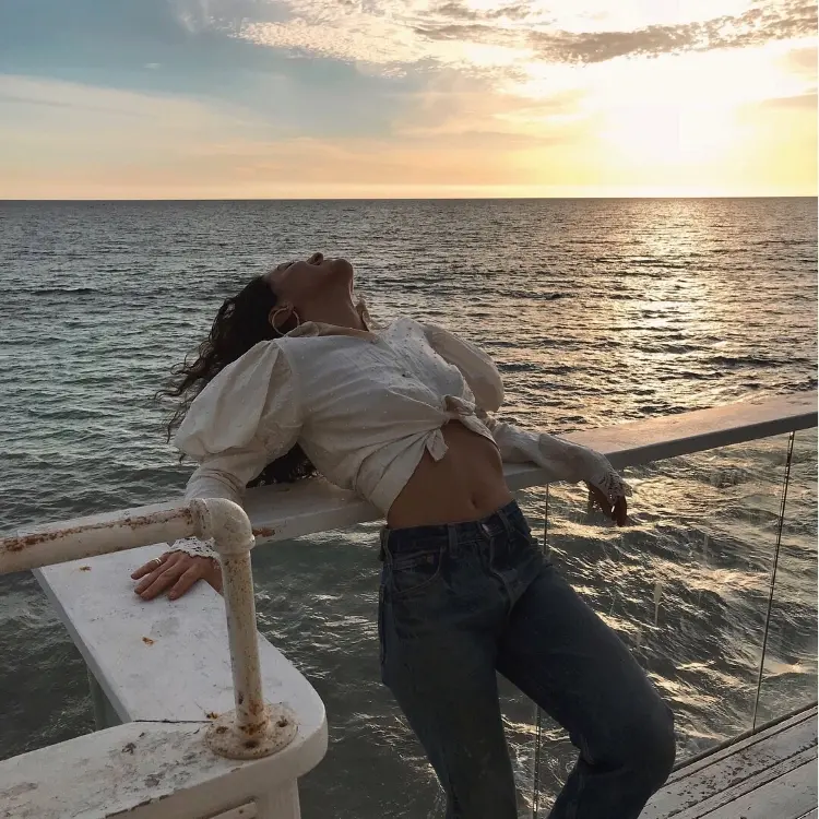 Frase para foto pensativa plus size mulher no barco em alto mar veste calça jeans e camisa branca com mangas bufantes Frase para foto pensativa