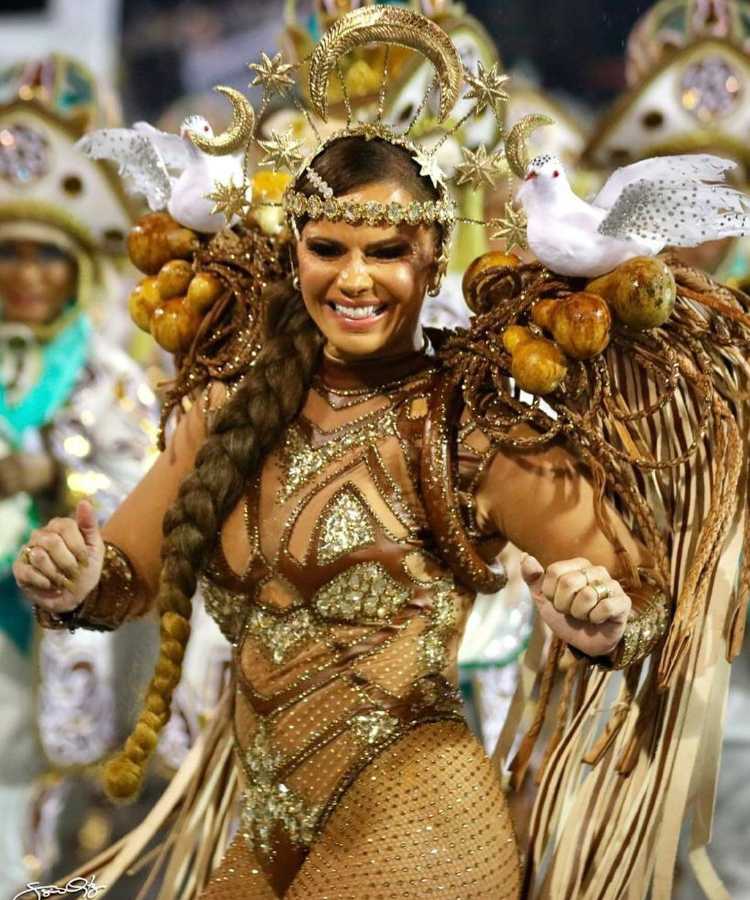 Viviane Araújo, atriz, fantasiada: fantasia dourada e marrom de pombas, luas e estrelas.