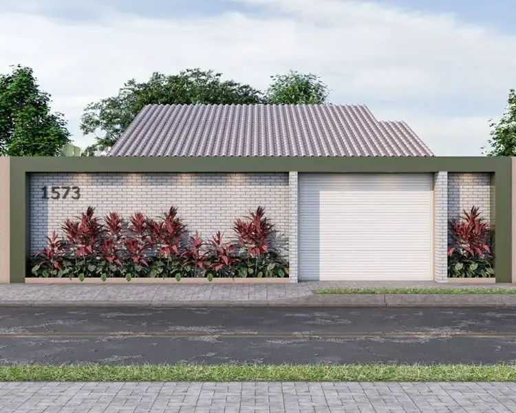 Fachada residencial moderna com muro de tijolos brancos, jardim com plantas ornamentais vermelhas, número "1573" à esquerda, portão de garagem branco à direita e moldura verde-oliva. Telhado cerâmico e árvores ao fundo em destaque.