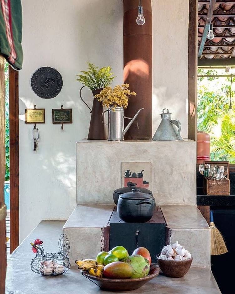 Fogão à lenha decorado com jarros com flores, panelas de ferro, ovos de galinha cesta de frutas, alho