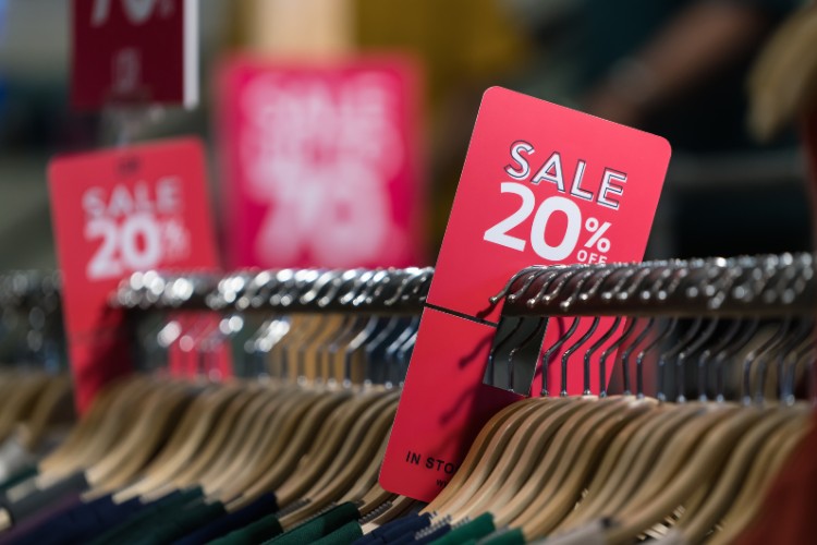 Arara com cabides e anúncio de promoção 20%