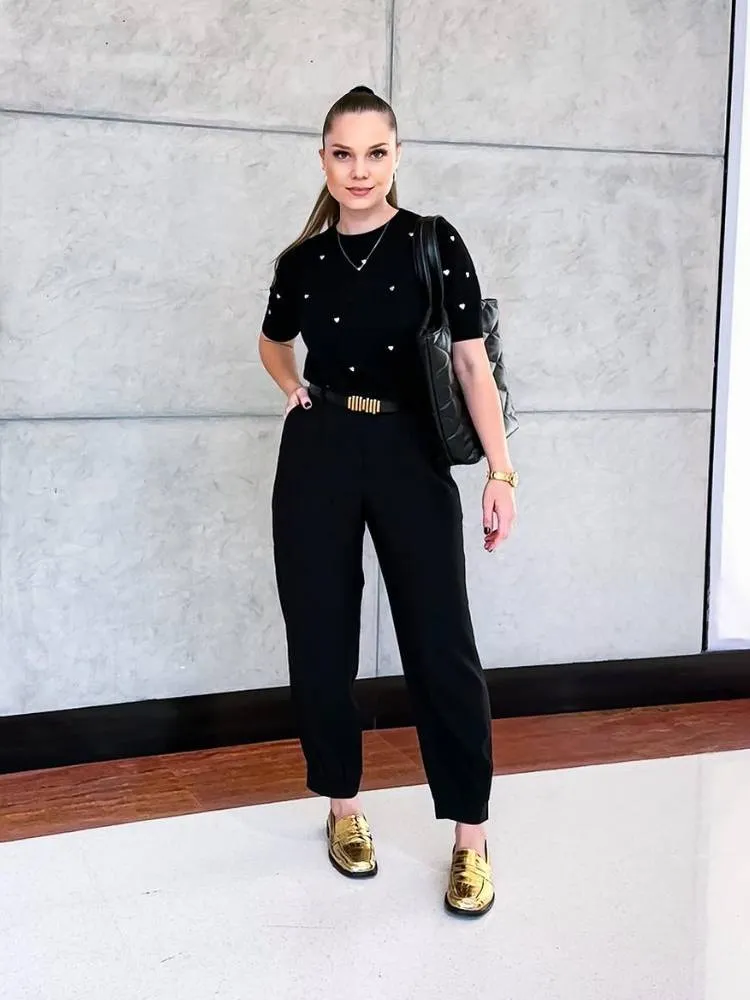 mulher usando look todo preto com mocassim dourado