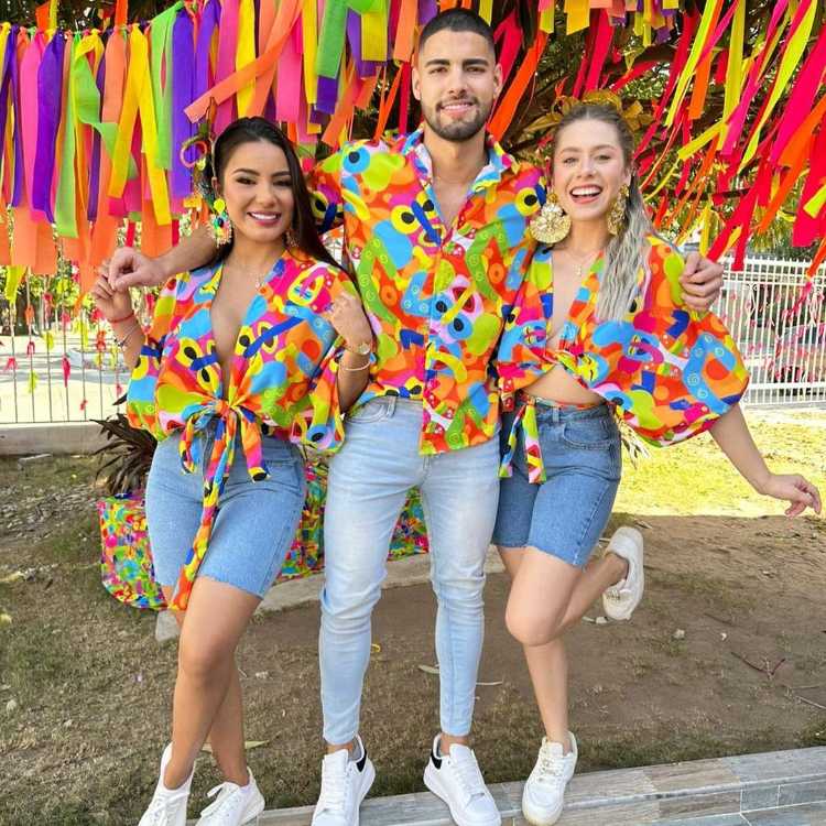 Duas mulheres e um homem usando blusas coloridas de mesma estampa e parte debaixo jeans