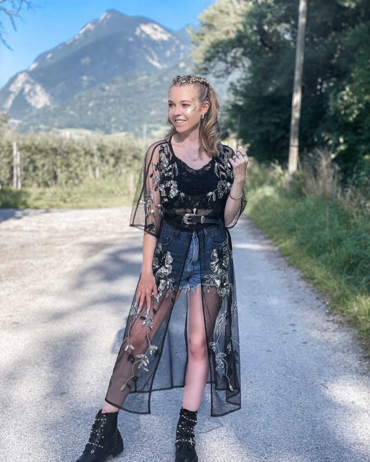 Mulher de pele clara usando kimono transparente bordado em dourado, cropped preto e shorts jeans