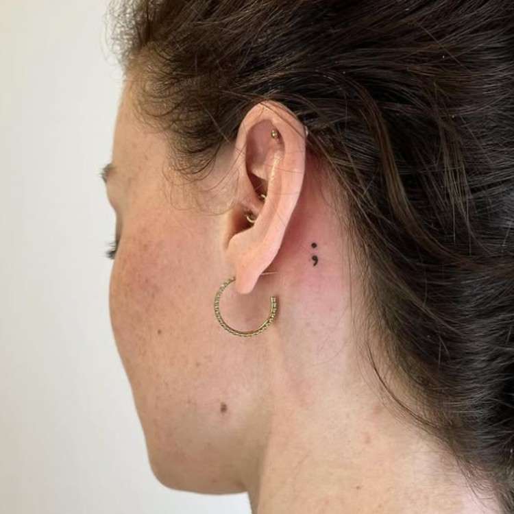 Mulher com tatuagem pequena de ponto e vírgula na nuca 