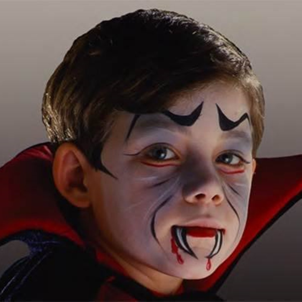 Menino com pintura de vampiro no rosto e fantasia. Menino com pintura de vampiro.
