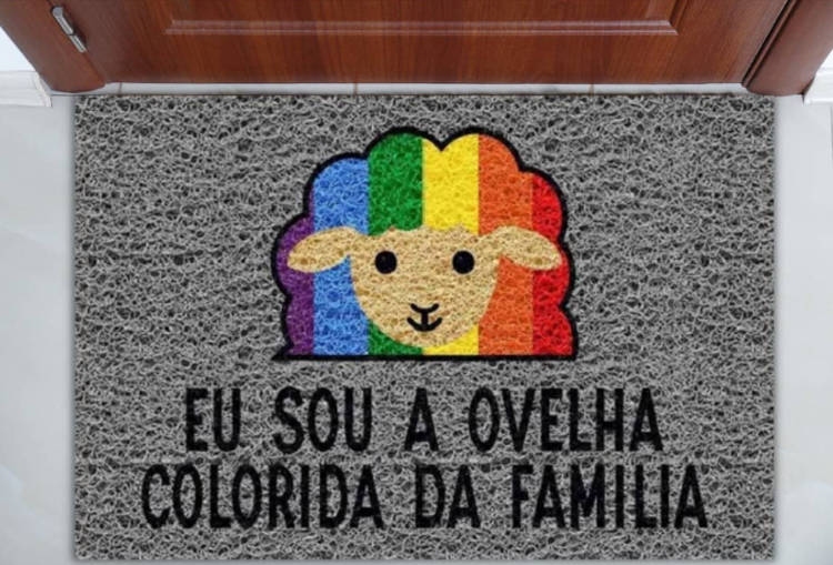 Tapete cinza para porta de entrada com desenho de ovelha colorida e frase "eu sou a ovelha colorida da família"