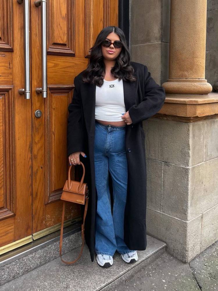 mulher usando regata branca com calça jeans e sobretudo preto