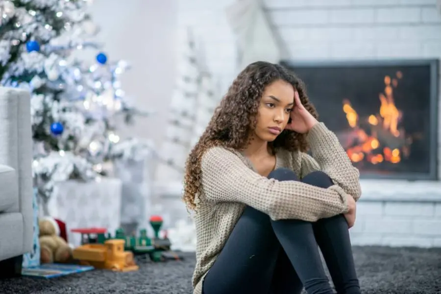 Jovem sentada no chão com depressão de fim de ano.
