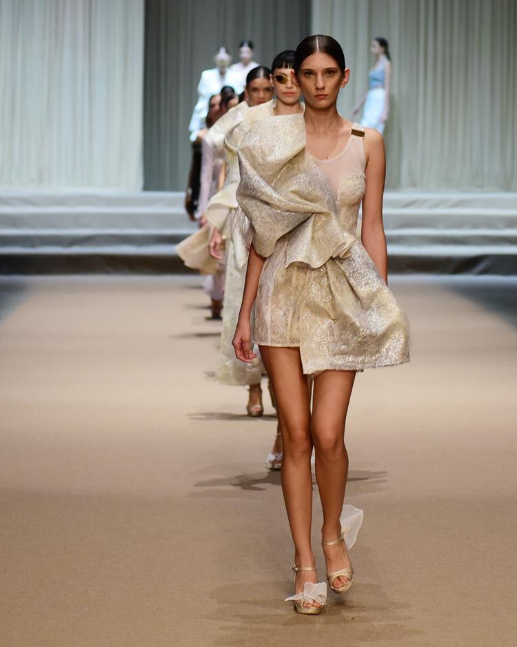 modelo no desfile Melk Z-Da com vestido curto branco e dourado