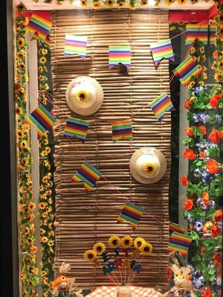 Vitrine com esteira pendurada, chapéus de palha e bandeirinhas nas cores LGBT